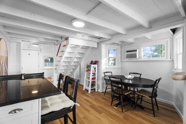 dining room featuring cooling unit, beam ceiling, and light hardwood / wood-style flooring