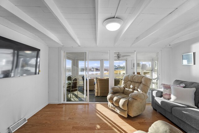 living room featuring beam ceiling, hardwood / wood-style flooring, and ceiling fan