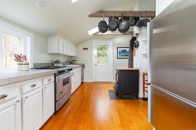 kitchen with a wealth of natural light, white cabinetry, appliances with stainless steel finishes, and light wood-type flooring