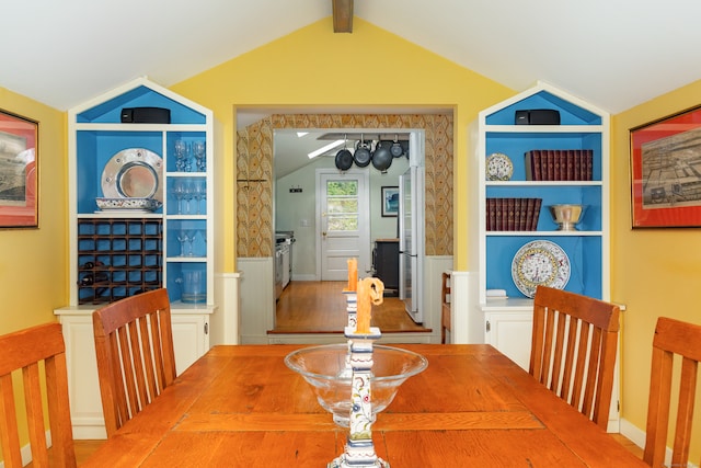 dining room with lofted ceiling with beams, hardwood / wood-style flooring, and built in shelves