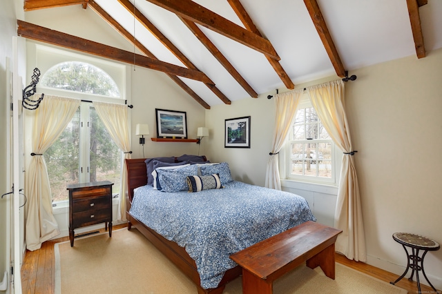 bedroom with lofted ceiling with beams, multiple windows, and light hardwood / wood-style flooring