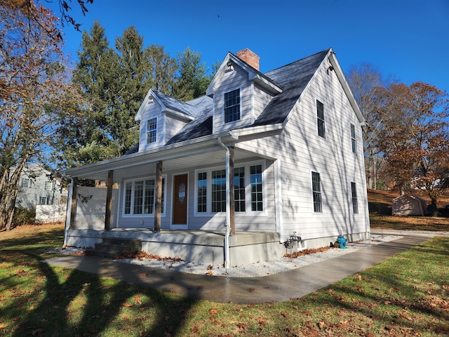 cape cod-style house featuring covered porch and a front yard