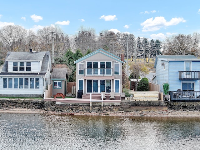 back of property featuring a storage unit and a deck with water view