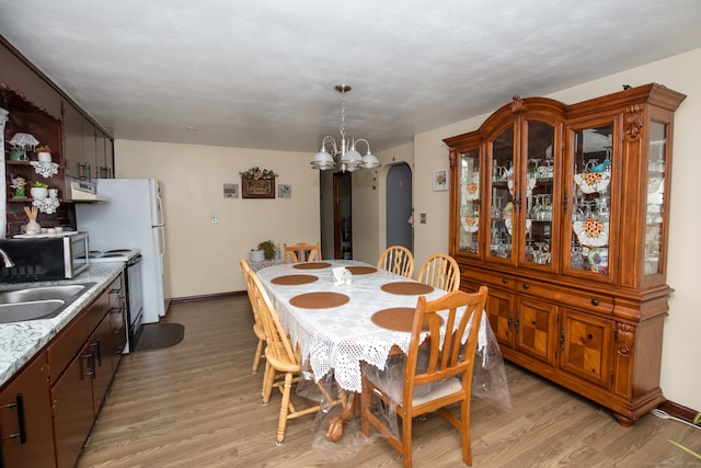 dining space with a chandelier, sink, and light wood-type flooring