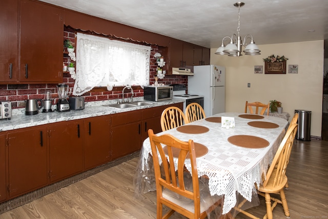 dining area featuring light wood-type flooring, sink, and an inviting chandelier