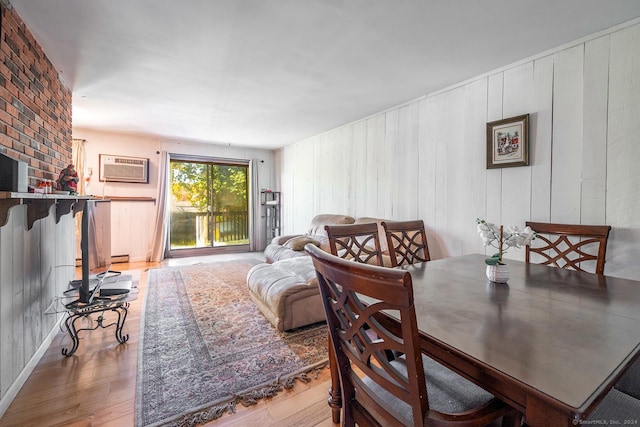 dining room featuring a wall unit AC, wood-type flooring, and baseboard heating