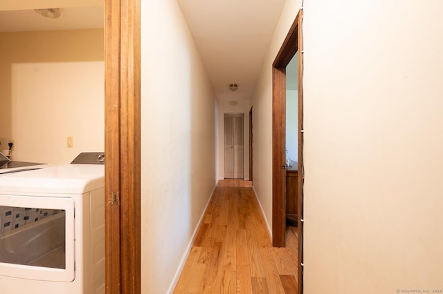 hallway with washer and dryer and light hardwood / wood-style flooring