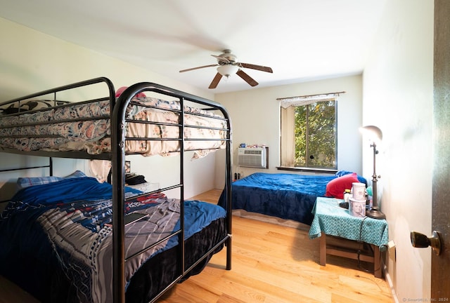 bedroom with wood-type flooring, an AC wall unit, and ceiling fan