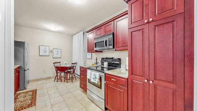 kitchen featuring stainless steel appliances, light tile patterned floors, and light stone countertops