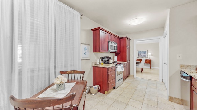 kitchen featuring stainless steel appliances, light tile patterned flooring, and light stone countertops