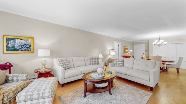 living room with a baseboard radiator, an inviting chandelier, crown molding, and light hardwood / wood-style flooring