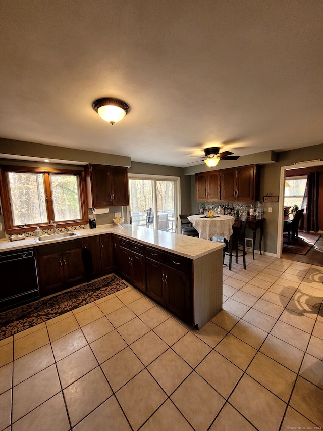 kitchen with dishwasher, kitchen peninsula, a wealth of natural light, and dark brown cabinets