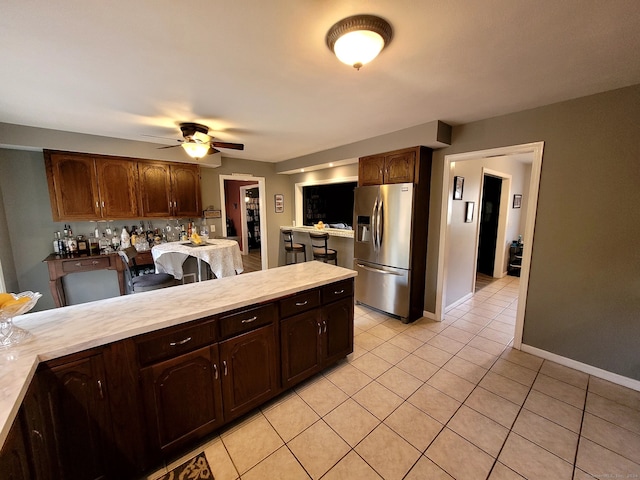 kitchen featuring ceiling fan, dark brown cabinets, light tile patterned floors, and stainless steel fridge