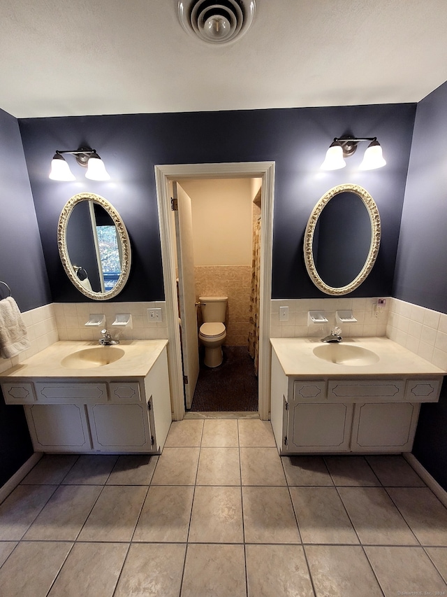 bathroom with vanity, tile patterned floors, toilet, and tile walls