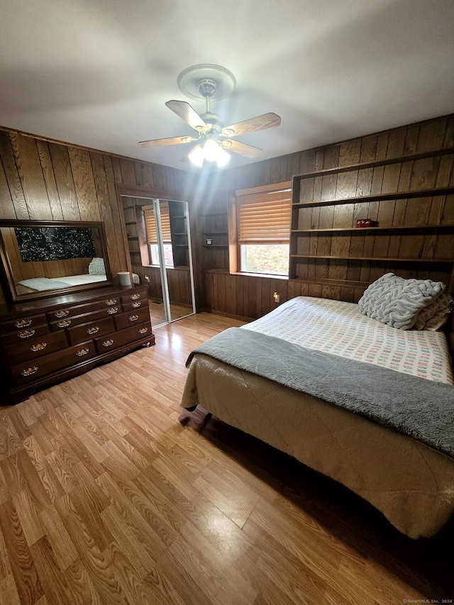 bedroom with wooden walls, ceiling fan, and light hardwood / wood-style flooring