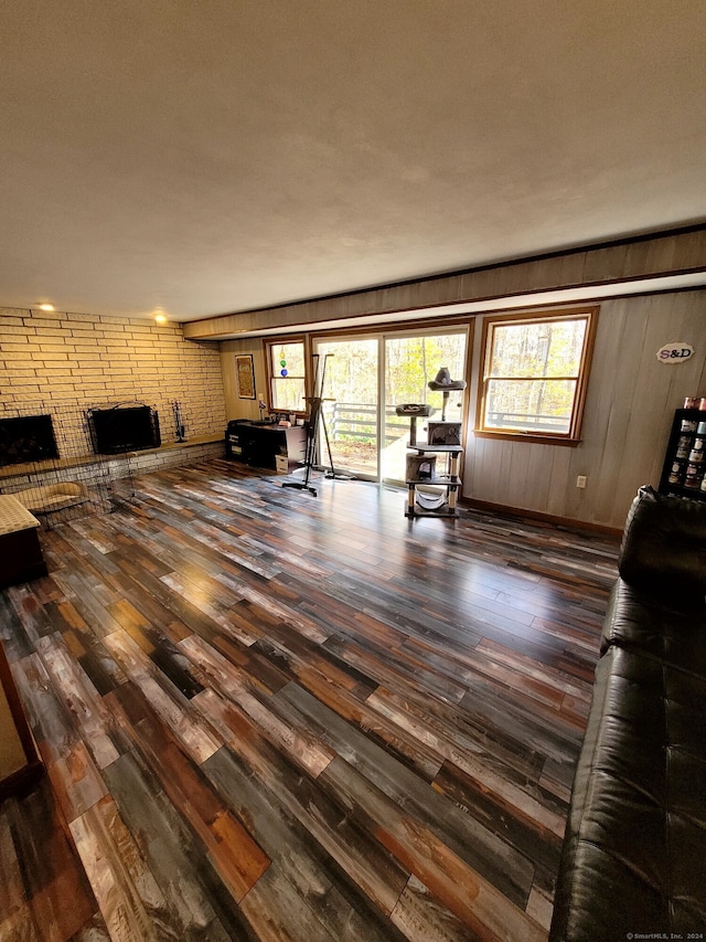 unfurnished living room featuring a brick fireplace, hardwood / wood-style floors, and wood walls