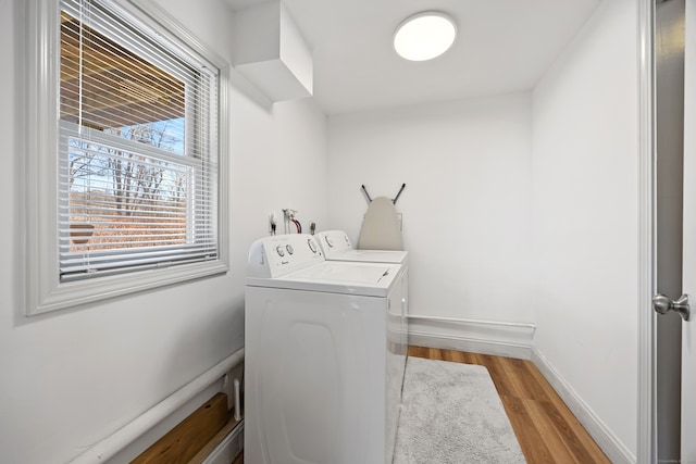 laundry room with washing machine and dryer and light hardwood / wood-style flooring