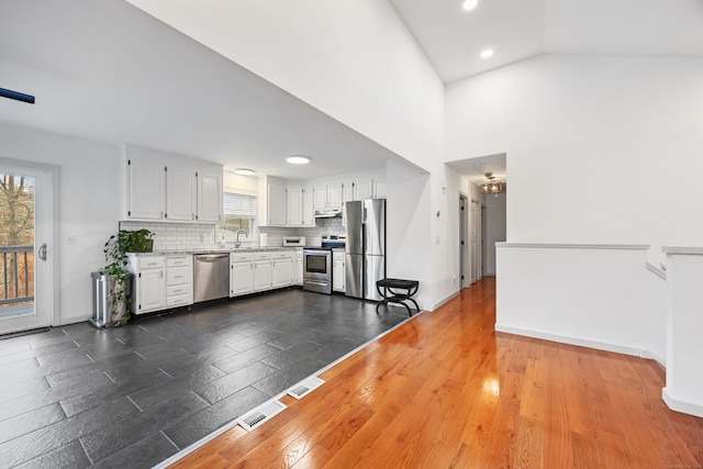 kitchen with dark wood-type flooring, white cabinets, sink, appliances with stainless steel finishes, and tasteful backsplash