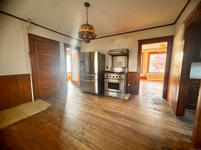 kitchen with wooden walls, ceiling fan with notable chandelier, hardwood / wood-style flooring, and stainless steel appliances