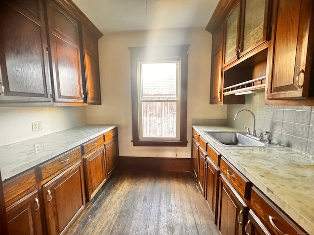 kitchen featuring dark hardwood / wood-style floors, sink, light stone counters, and decorative backsplash