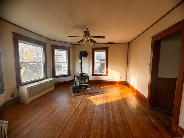 unfurnished living room with dark hardwood / wood-style flooring, radiator heating unit, a wood stove, and ceiling fan