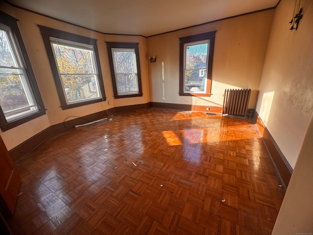 unfurnished room with radiator heating unit and dark parquet flooring