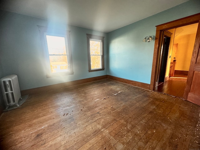 unfurnished room with radiator heating unit and hardwood / wood-style flooring