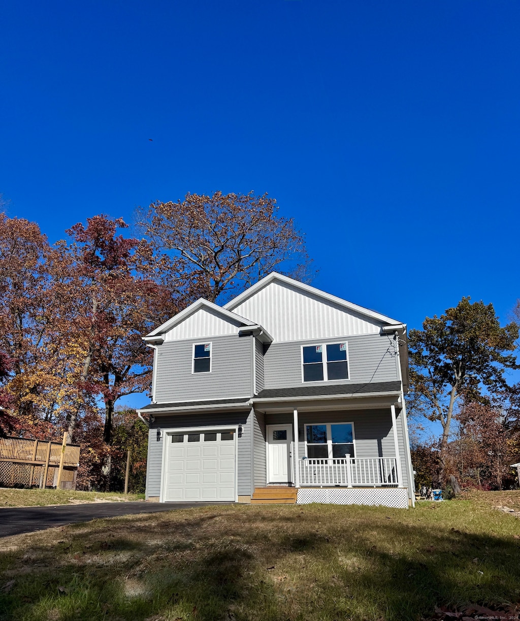 view of front of house with a porch, a front yard, and a garage