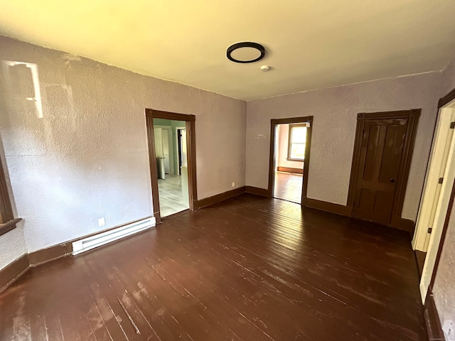 spare room featuring a baseboard radiator and dark hardwood / wood-style flooring