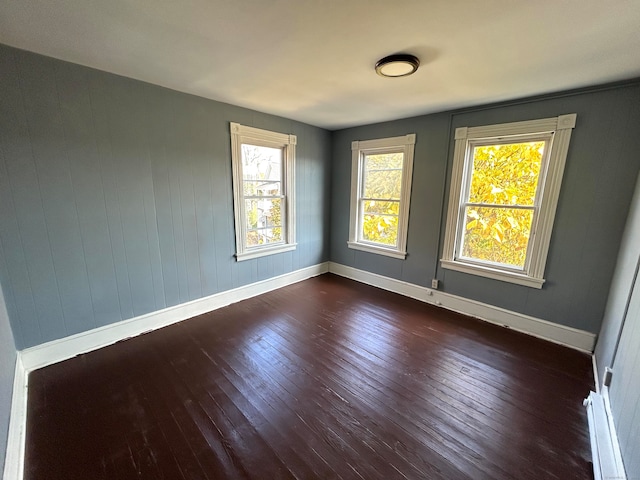 empty room with dark hardwood / wood-style flooring and wood walls