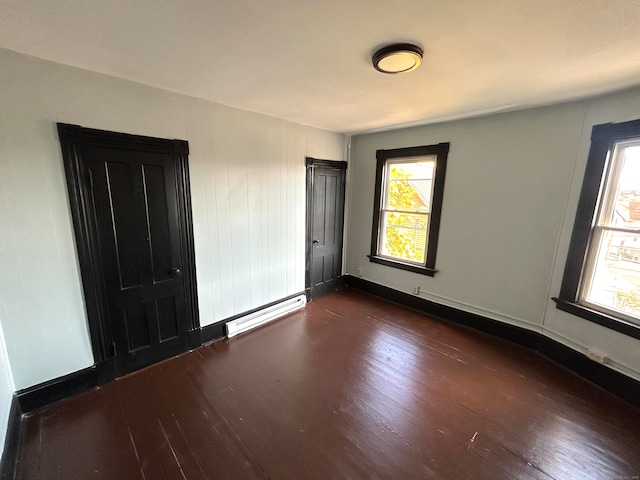 unfurnished bedroom featuring dark hardwood / wood-style floors and a baseboard radiator