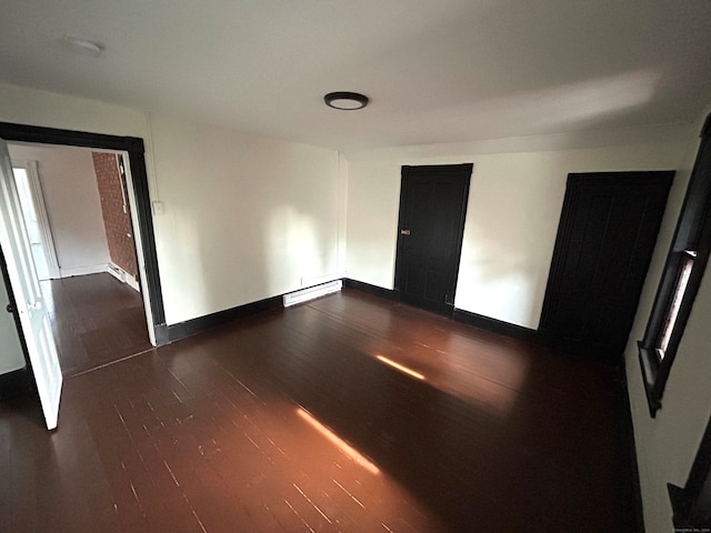 unfurnished room featuring dark hardwood / wood-style floors and a baseboard heating unit