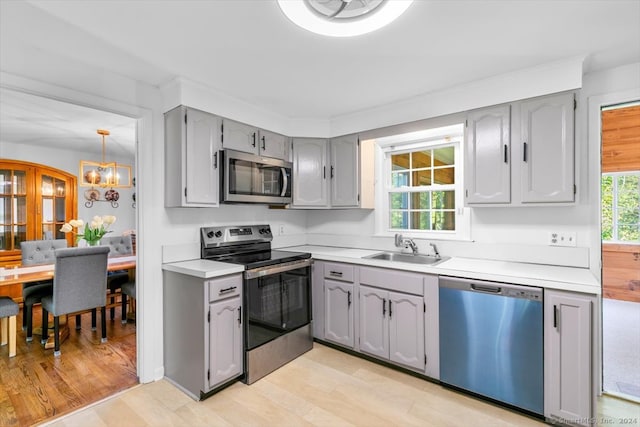 kitchen featuring gray cabinetry, light wood-type flooring, sink, and stainless steel appliances