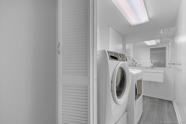 laundry area featuring cabinets, light hardwood / wood-style floors, and washer / dryer