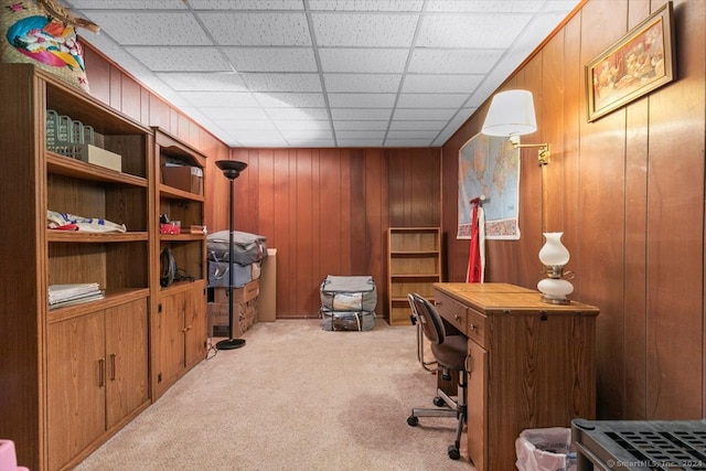 carpeted office featuring wood walls and a drop ceiling