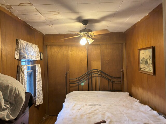 bedroom with ceiling fan and wooden walls