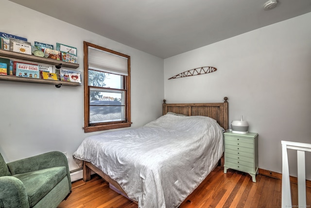 bedroom with baseboard heating and dark hardwood / wood-style floors