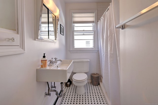 bathroom with tile patterned flooring, toilet, walk in shower, and sink