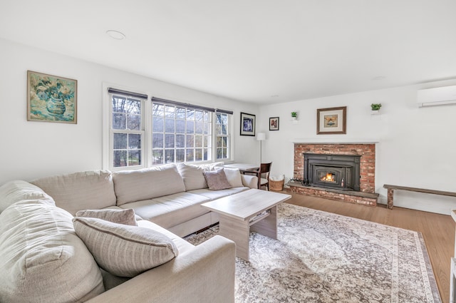 living room featuring a wall mounted AC, light hardwood / wood-style flooring, and a fireplace