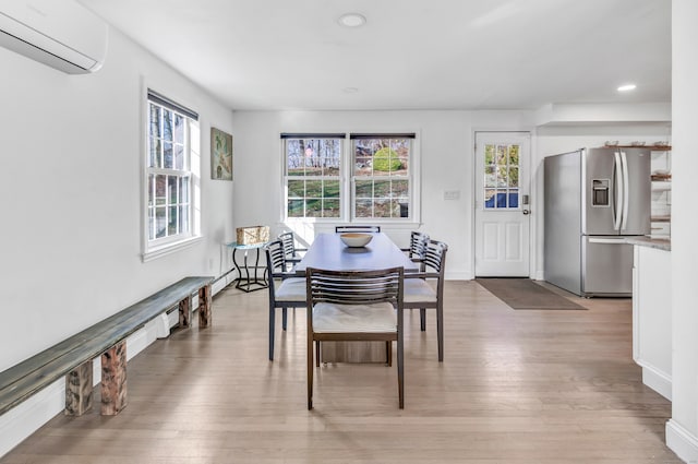 dining room featuring a wall mounted AC and light wood-type flooring