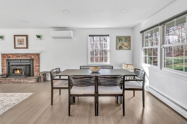 dining room featuring an AC wall unit, plenty of natural light, light hardwood / wood-style flooring, and a baseboard heating unit