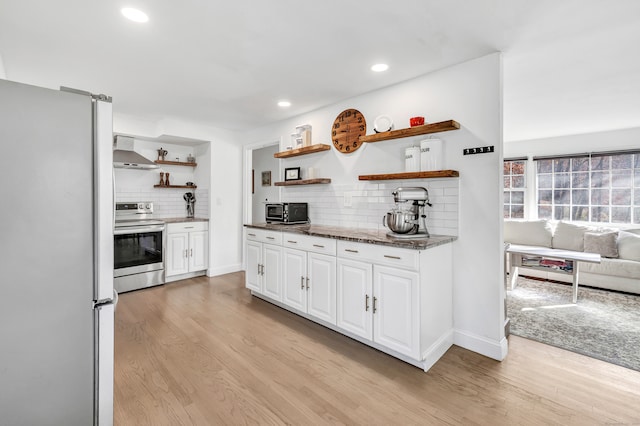 kitchen featuring light hardwood / wood-style flooring, wall chimney exhaust hood, stainless steel range oven, and white refrigerator