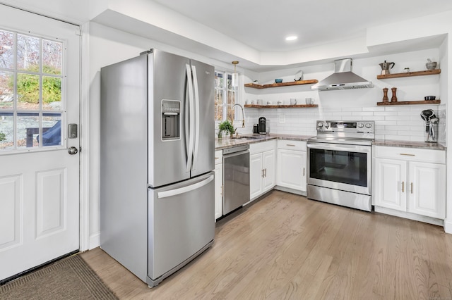 kitchen with white cabinetry, sink, wall chimney exhaust hood, appliances with stainless steel finishes, and light wood-type flooring