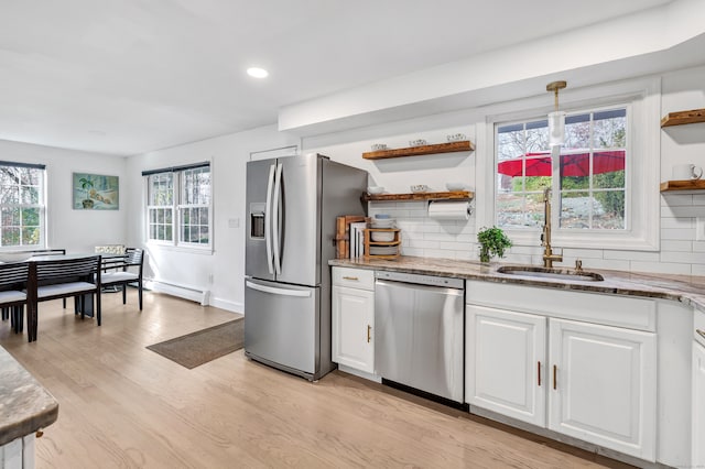 kitchen with light hardwood / wood-style flooring, baseboard heating, appliances with stainless steel finishes, tasteful backsplash, and white cabinetry