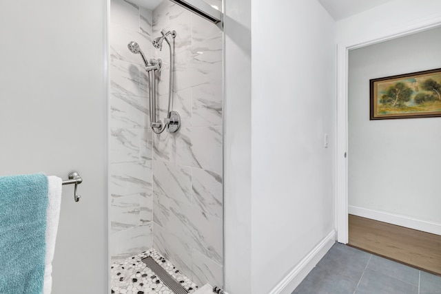 bathroom with tiled shower and wood-type flooring