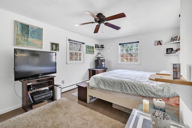 bedroom with dark wood-type flooring, ceiling fan, and a baseboard heating unit