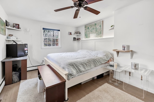 bedroom with ceiling fan, light hardwood / wood-style floors, and a baseboard radiator