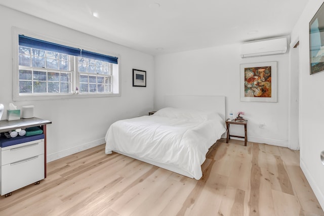 bedroom with a wall unit AC and light hardwood / wood-style floors