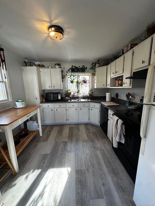 kitchen with black appliances, dark hardwood / wood-style flooring, white cabinets, and a healthy amount of sunlight