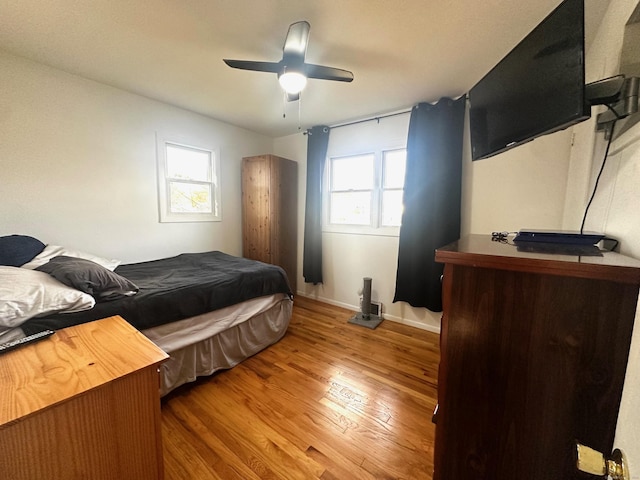 bedroom with hardwood / wood-style flooring, ceiling fan, and multiple windows